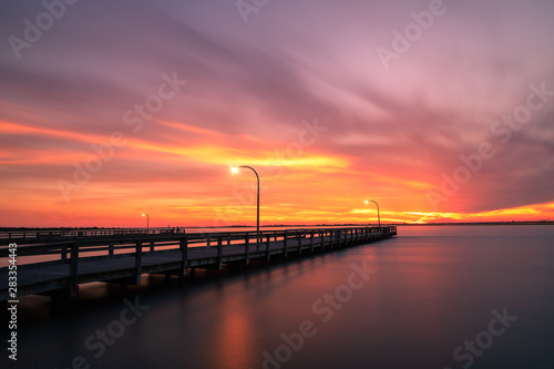 Vibrant colors light up the sky just after sunset over a long fishing pier. Jones Beach, Long Island New York