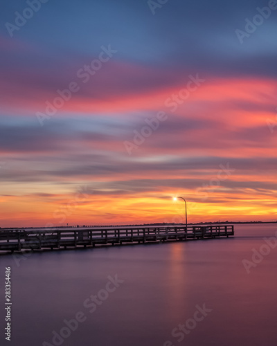 Vibrant colors light up the sky just after sunset over a long fishing pier. Jones Beach, Long Island New York © Scott Heaney