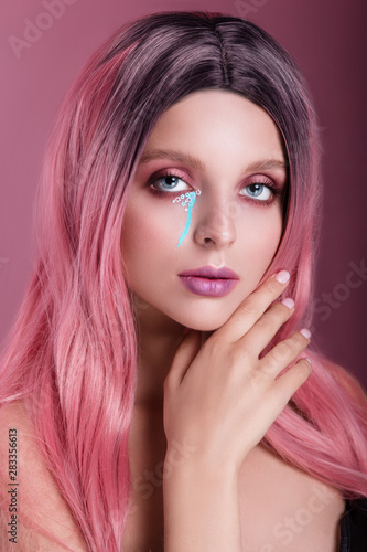 Beauty fashion model girl with colorful dyed pink hair and creative make-up on pink backround.