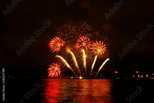 Beautiful colorful fireworks in sky over river. Big festive evening event with great pyrotechnic show.  