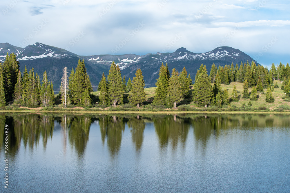 Colorado landscape of snow capped mountains and trees reflected in Little Molas Lake in the San Juan Mountains