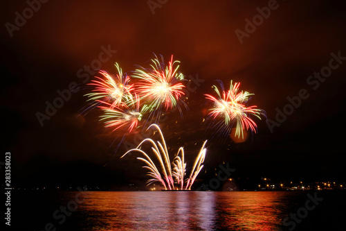 Beautiful colorful fireworks in sky over river. Big festive evening event with great pyrotechnic show.  