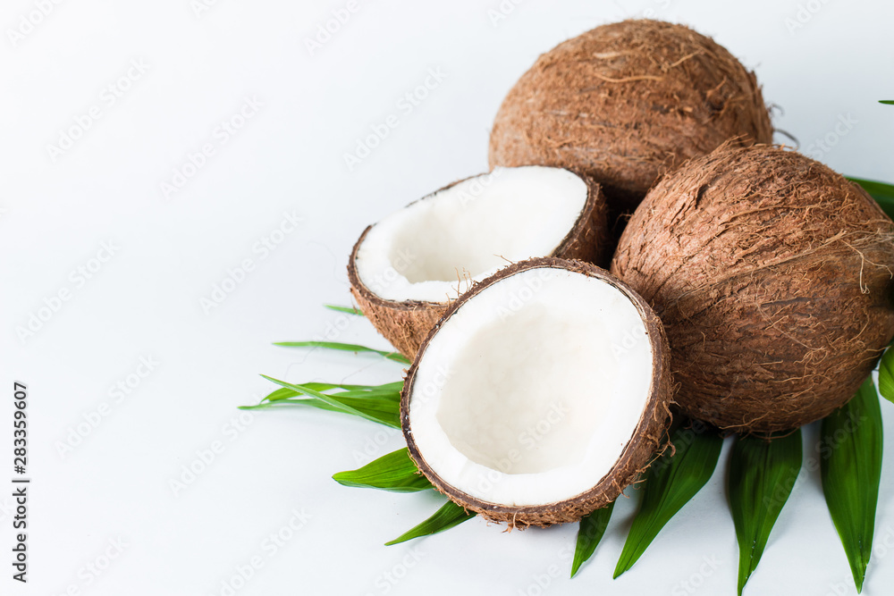 Ripe half cut coconut with green leaves on a white background. Isolated concept. Ripe half cut coconut with green leaves on a white background. Isolated concept.