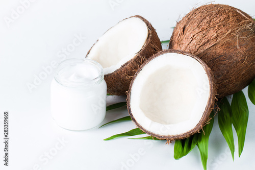 Ripe half cut coconut and cream with green leaves on a white isolated background. Healthcare and medical concept. Skin care.