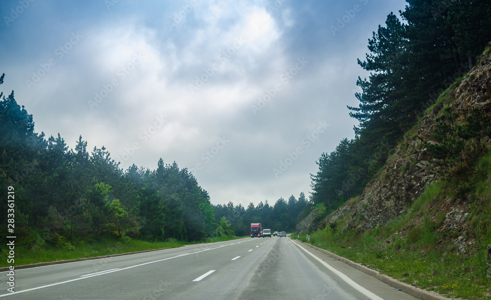 Road that goes through a countryside with traffic in distance Road that goes through a countryside with traffic in distance