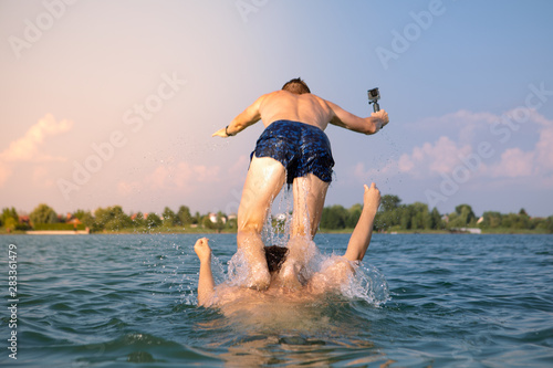 couple of males friends having fun in lake taking selfie on action camera