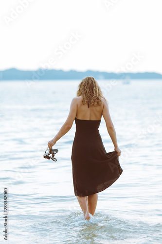 woman in black dress walking in water at sea beach
