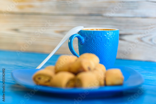 Shortbread biscuits on a cream plate on a wooden background, rd cup of coffee.