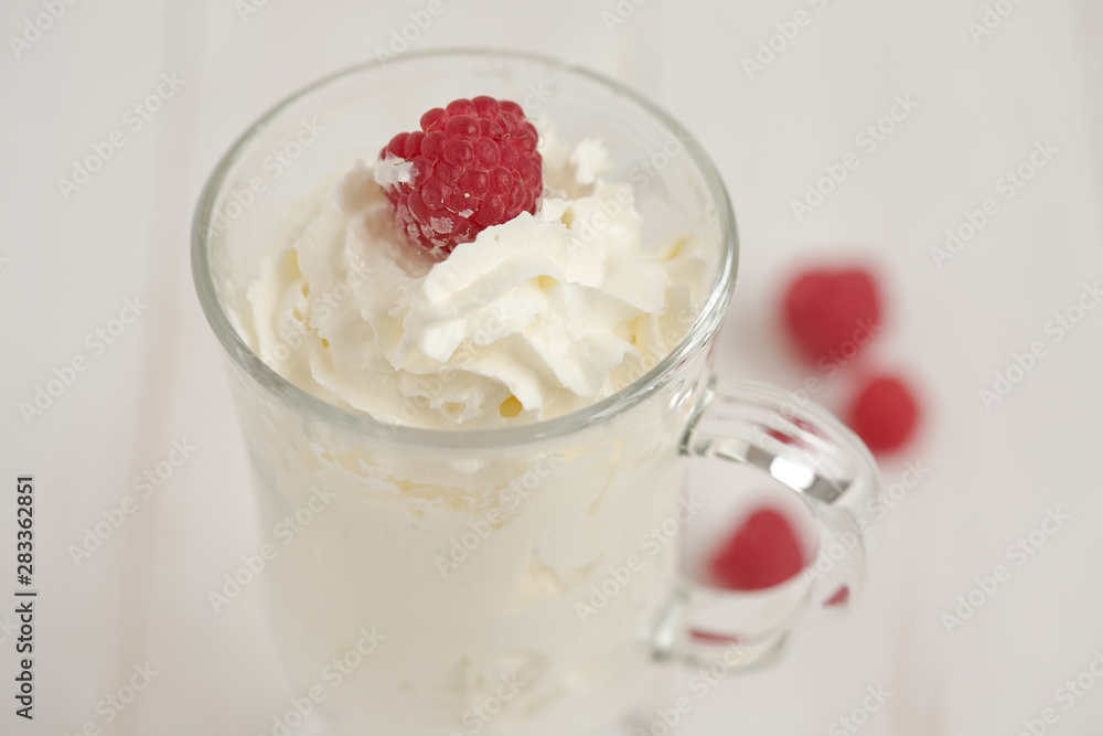 Glass with whipped cream and raspberries. Close-up
