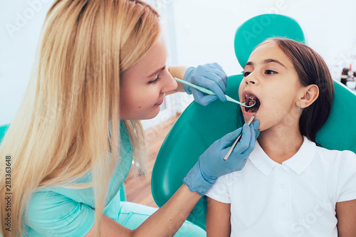 Little girl getting teeth exam by pediatric dentist at clinic