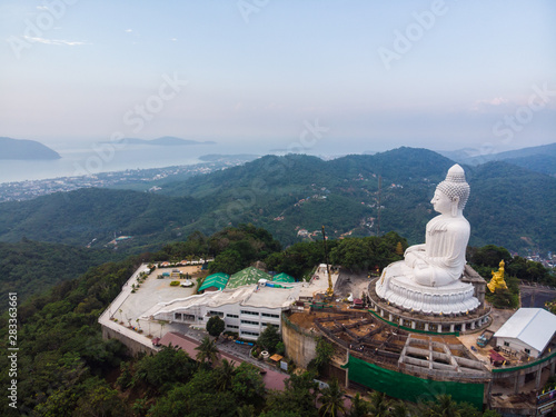 Big white buddhist monk on top of mountain peak sunrise sky aerial view