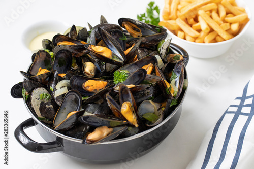 Belgian mussels with potato fries and sauce on white marble table