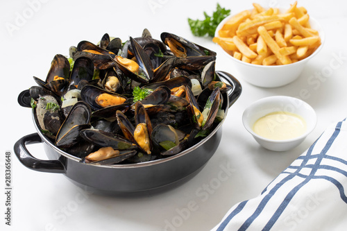 Belgian mussels with potato fries and sauce on white marble table