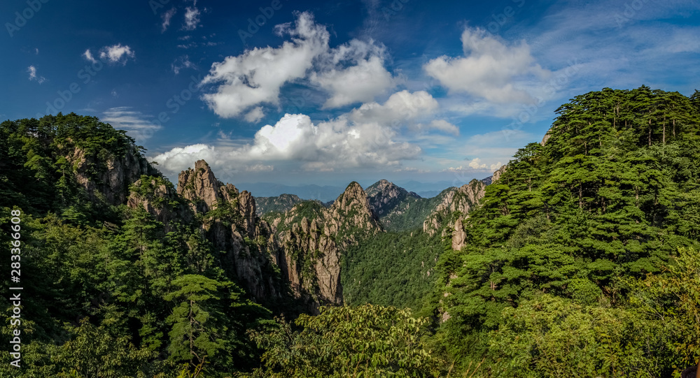 Lush green trees and bushes with steep yellow peaks in the middle in Huang Shan (黄山, Yellow Mountains) China