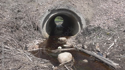 Big culvert under the highway. Before the pipe accumulates a large amount of natural and artificial debris. Before pipe flows the river, where this road debris gets photo