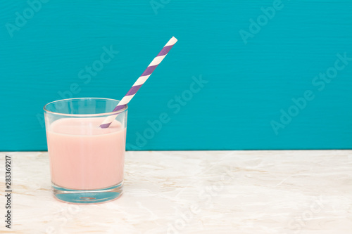 Delicious strawberry milkshake with a straw in a glass