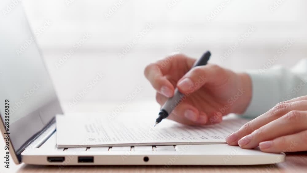 Woman freelancer working on laptop at home-office. Close up of female hands with paper documents. Businesswoman filling out tax return form at work. Pedestal shot Woman freelancer working on laptop at home-office. Close up of female hands with paper documents. Businesswoman filling out tax return form at work. Pedestal shot