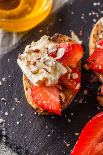 Bruschetta with strawberries, blue cheese, walnut and honey on stoyn plate photo