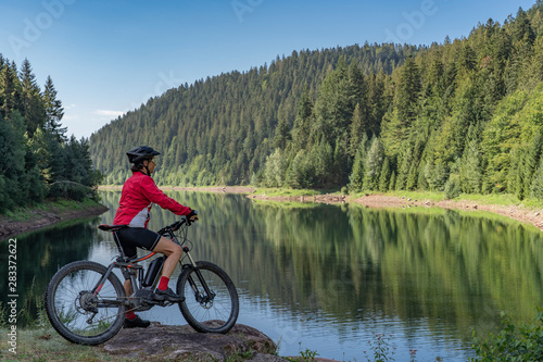 nice and ever young senior woman with her electric mountain bike at the Kinzig drinking Water reservoir in the northern Black Forest, Baden-Wuerttemberg, Germany