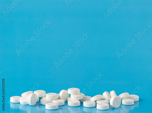 Heap of round white pills. Blue background with text space