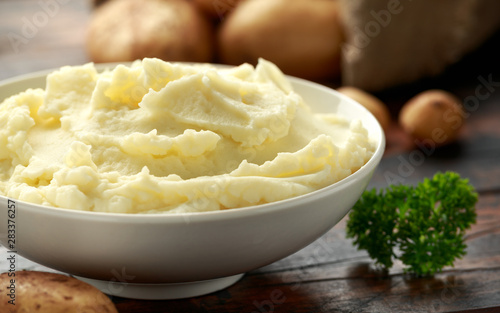 Mashed potatoes in white bowl on wooden rustic table. Healthy food