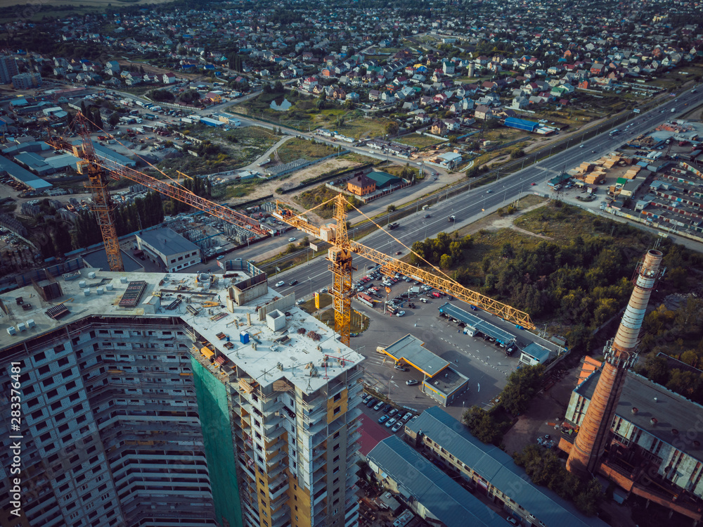 Modern building under construction with crane. Aerial view of constructing building with high crane in the evening
