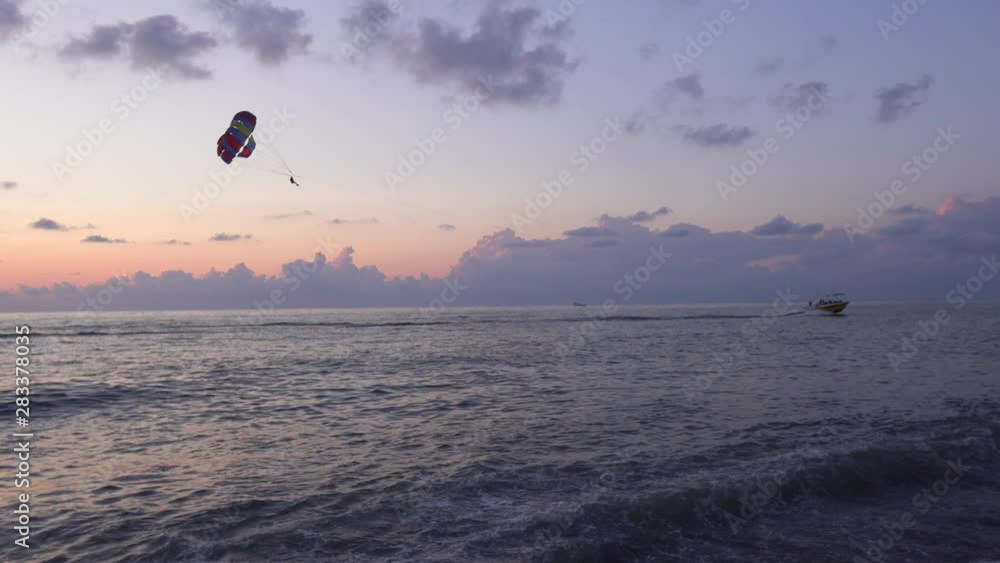 Parasailing in blue sea during orange evening sundown on horizon, beautiful scenery of tranquil seascape in summer evening twilights. Tourists on a parachute over the sea . 4K shot. Sunset paradise Parasailing in blue sea during orange evening sundown on horizon, beautiful scenery of tranquil seascape in summer evening twilights. Tourists on a parachute over the sea . 4K shot. Sunset paradise