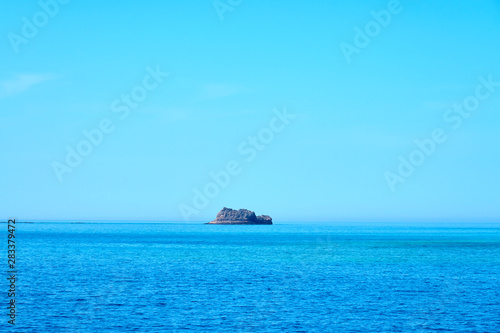 Rocky island in the middle of the sea. Natural background texture. Copy space.