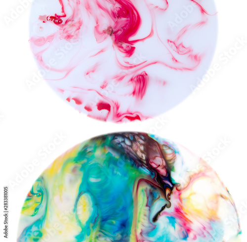 Two hemispheres with abstract waves and twists of food coloring on the surface of milk. Look like mysterious planets isolated on white background. Marangoni - Gibbs effect.