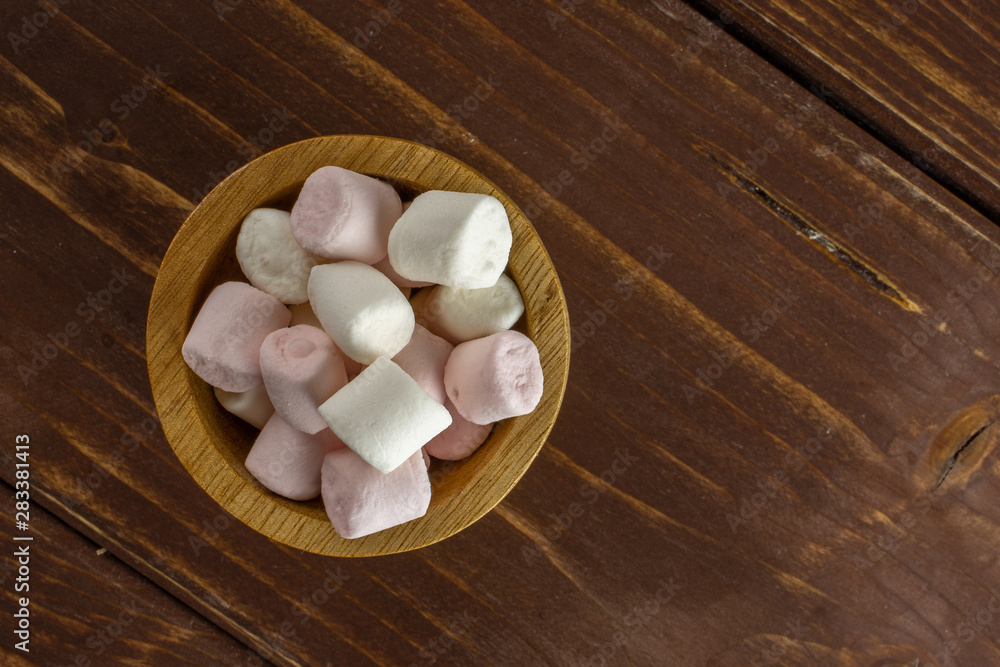 Lot of whole sweet fluffy marshmallow copyspace in wooden bowl flatlay on brown wood Lot of whole sweet fluffy marshmallow copyspace in wooden bowl flatlay on brown wood