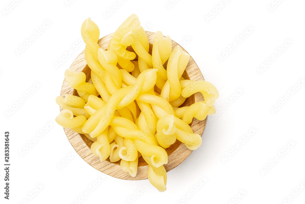 Lot of whole raw pasta gemelli in wooden bowl flatlay isolated on white background