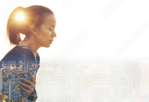 Close up of a businesswoman with crossed arms against a morning city panorama.