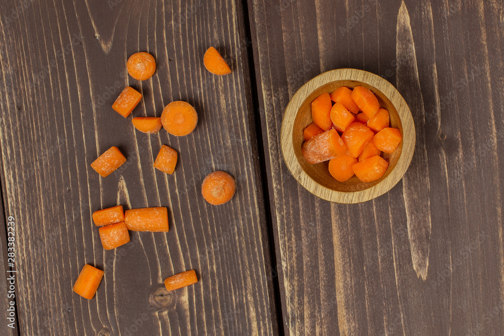 Lot of pieces of stale orange stale baby carrot baby in wooden cup flatlay isolated on brown wood Lot of pieces of stale orange stale baby carrot baby in wooden cup flatlay isolated on brown wood