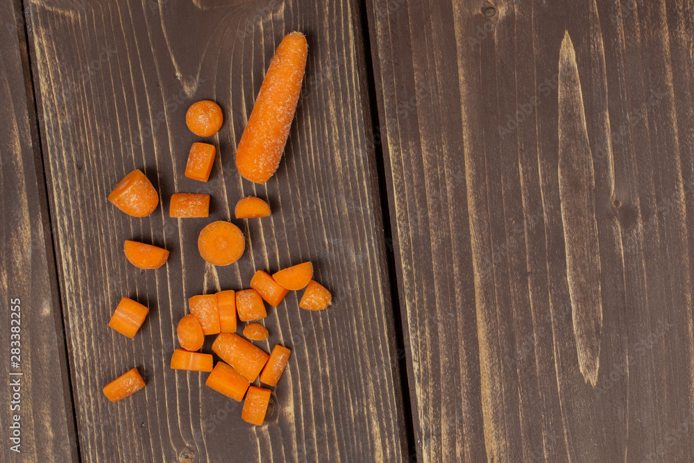 One whole lot of pieces of stale orange stale baby carrot baby in a wooden bowl flatlay isolated on brown wood One whole lot of pieces of stale orange stale baby carrot baby in a wooden bowl flatlay isolated on brown wood
