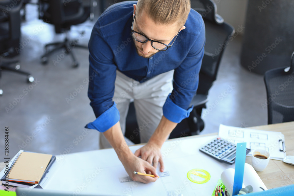 Good looking young man drawing something while working in the office. Good looking young man drawing something while working in the office.