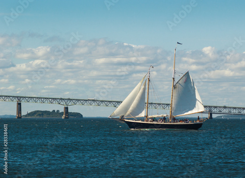 Two-masted sailing yacht in front of Newport Bridge, Rhode Island