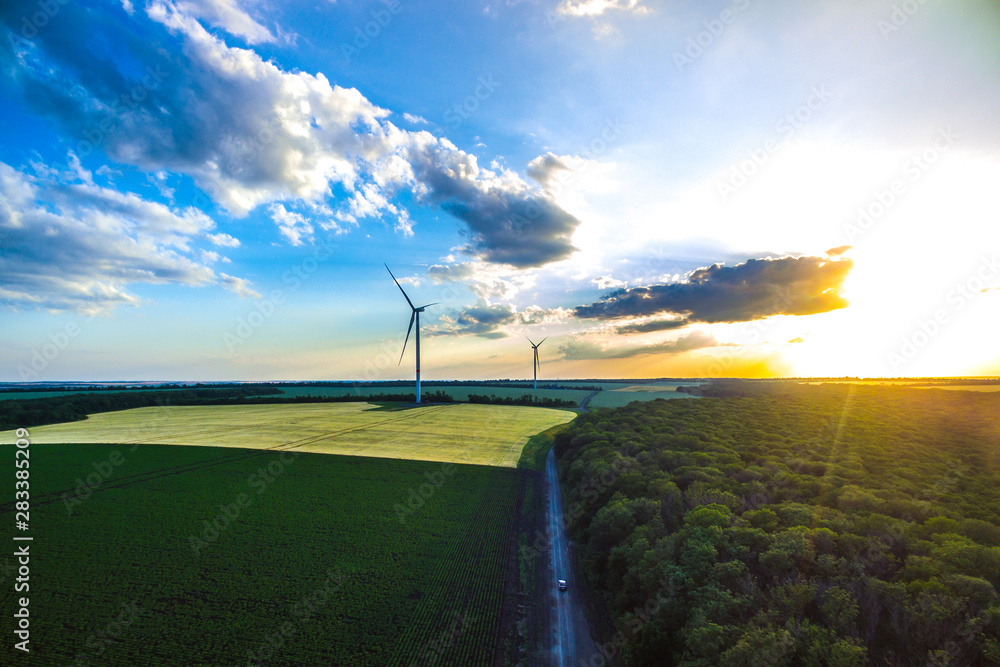 wind generators among the fields at sunset. Windmills by the countryside. New technology. Renewable energy. shot on a drone wind generators among the fields at sunset. Windmills by the countryside. New technology. Renewable energy. shot on a drone