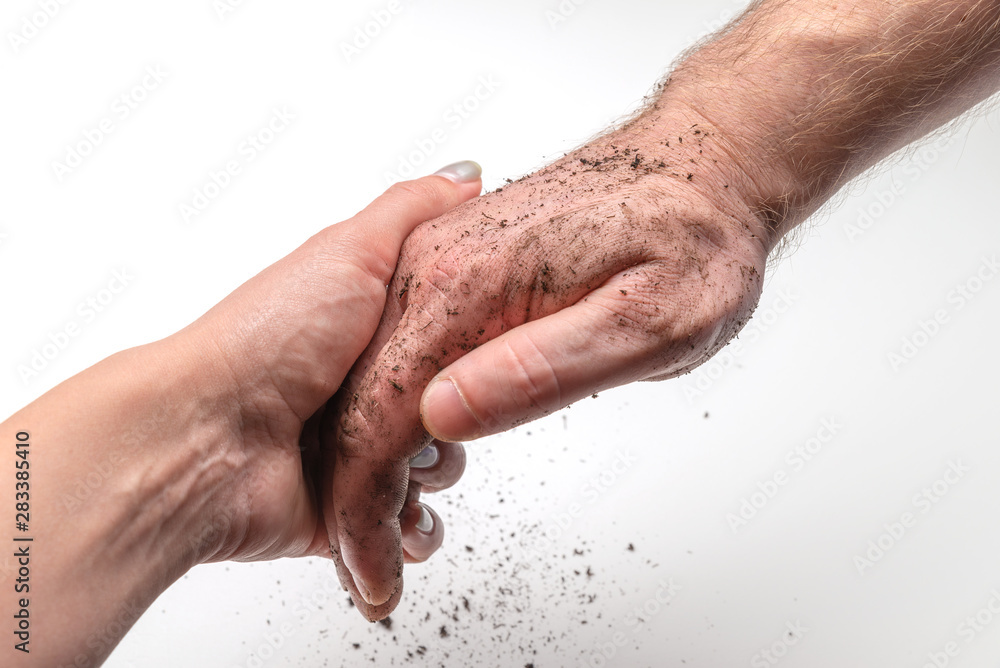 Female hand is keeping male dirty hand on the white background. International Day to Assist the Poor Female hand is keeping male dirty hand on the white background. International Day to Assist the Poor