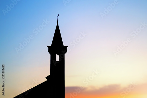 Fototapeta dark silhouette of a muslim mosque with a crescent on the spire at sunset