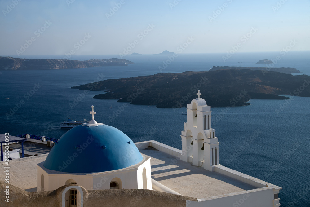 Church of Aghioi Theodoroi in Firostefani on Santorini one of the Cycladic islands in the Aegean Sea, Greece. View of the volcano Tholos Naftilos. The most famous blue dome on the island.