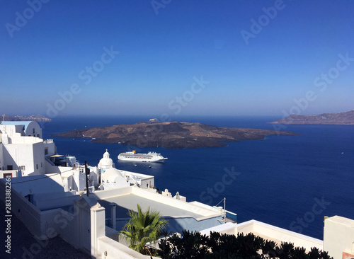 Typical houses of Oia in Santorini volcanic island of the Aegean Sea in Greece. A cruise ship on the caldera gulf and view of the island with the volcano of Nea Kameni.