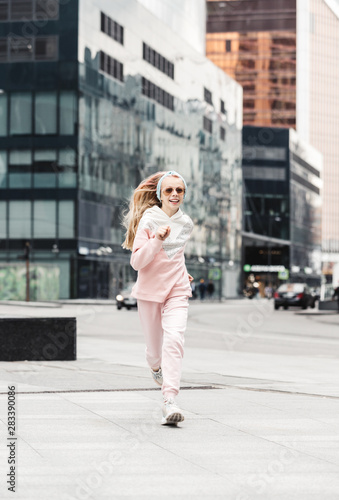 Beautiful stylish girl run on the street of a large modern city.