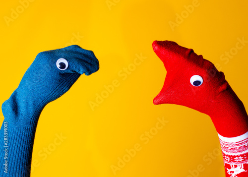 Red and blue sock puppets argue on the colorful yellow background