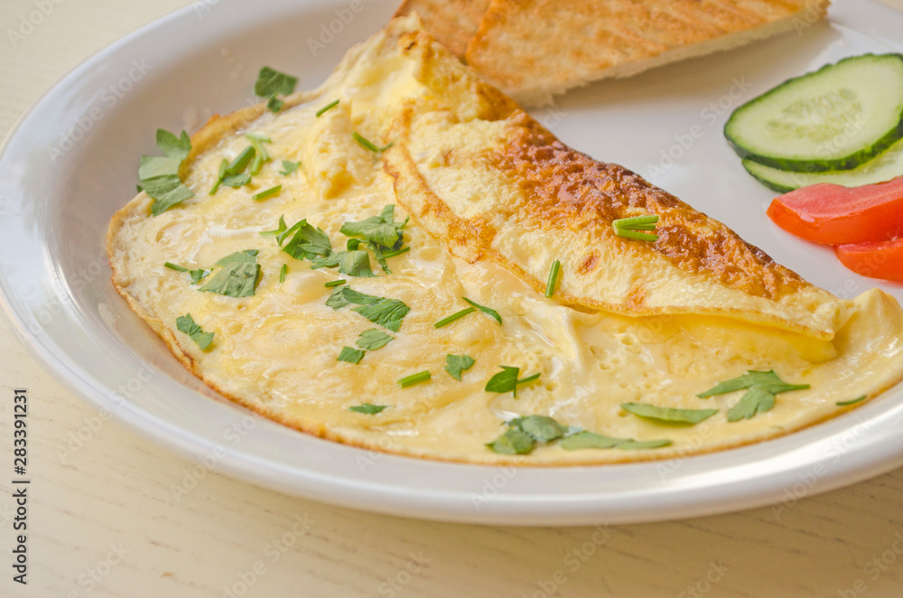 Omelet with cheese and parsley, sliced tomatoes and cucumbers on the plate. Scrambled eggs close-up. Healthy breakfast and lunch. Omelet with cheese and parsley, sliced tomatoes and cucumbers on the plate. Scrambled eggs close-up. Healthy breakfast and lunch.