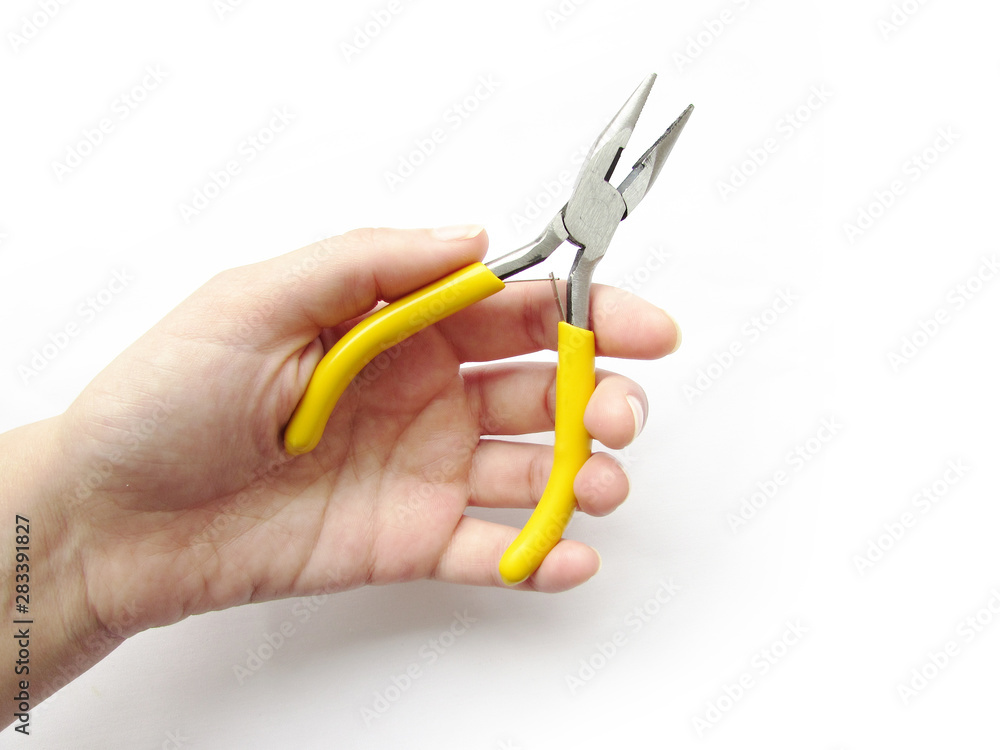 Small thin-nose pliers with bright yellow handles in the left hand isolated object on a white background. Small thin-nose pliers with bright yellow handles in the left hand isolated object on a white background.