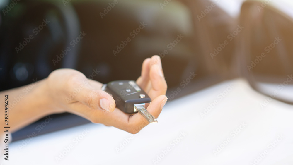 Obraz premium close up driver chauffeur adult man hand holding car's key and showing outside window for safety and insurance concept