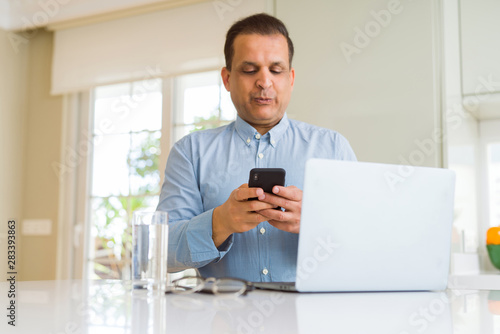 Middle age man working with laptop and using smartphone