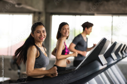 Asian friends run on machine at gym
