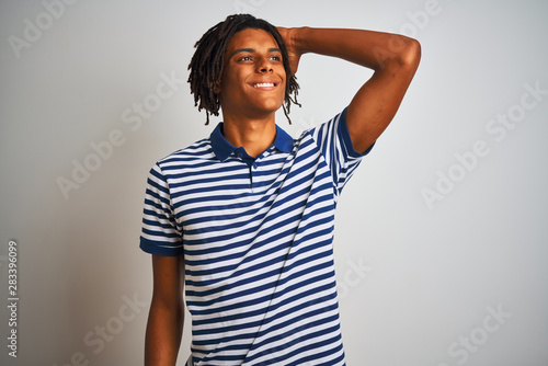 Afro man with dreadlocks wearing striped blue polo standing over isolated white background smiling confident touching hair with hand up gesture  posing attractive and fashionable