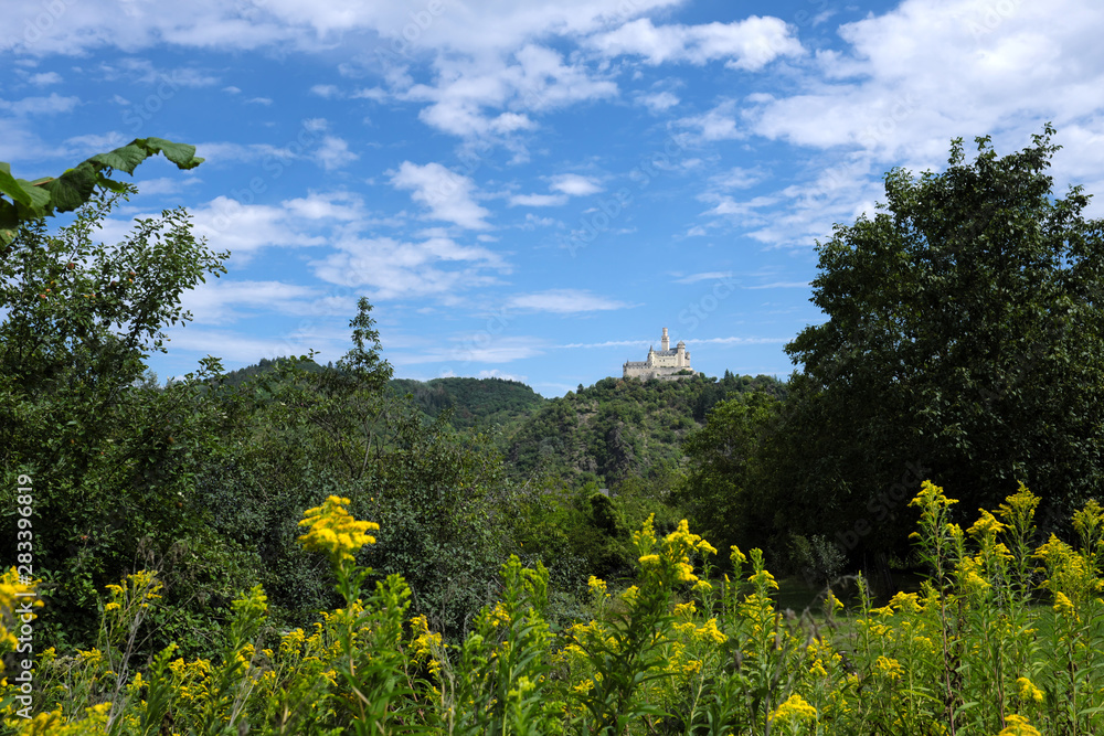 German castle Marksburg on the hill in the rhineland nad trees and blue sky with white clouds - Stockphoto